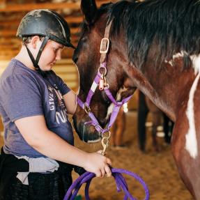 Program participant at Medicine Horse, an Equine Facilitated Therapy nonprofit, leans their forehead against a therapy horse's forehead. 