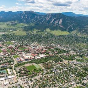 sweeping aerial view of boulder showing neighborhoods, streets and foothills in background