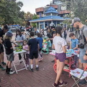 Children and adults interacting with an art station.