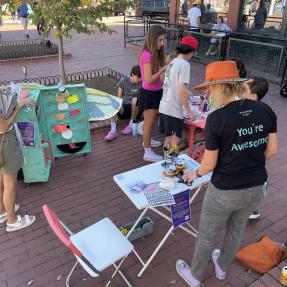 Children and adults interacting with an art station.