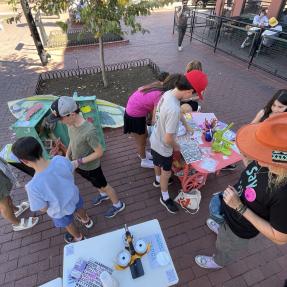 Children and adults interacting with an art station.
