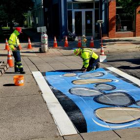 workers installing a mural crosswalk