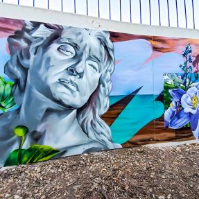 Colorful mural on side of a building featuring a statue bust and flowers