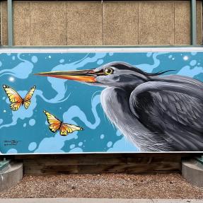 A mural of a bird and butterflies in front of a blue background