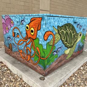Mural on all sides of an electrical box representing an ocean scene with visuals of ocean motifs