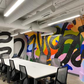 A mural with a colorful collage in the background and thick squiggly lines in the front