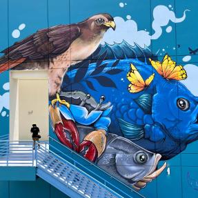 A large-scale mural of a bird in front of sea creatures 