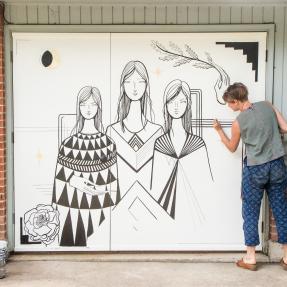 Artist installing mural artwork on a garage door