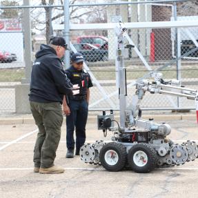 A Boulder Police Officer demonstrating use of an explosives detection robot with a kid in a police uniform