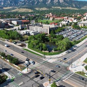 28th and Colorado intersection from above with the flatirons in the background. Buses, cars, bikes and people walking travel. 