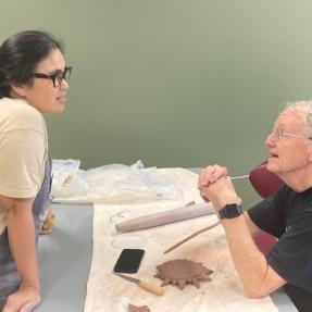 A pottery class participants listens to the instructor's tips on working with clay