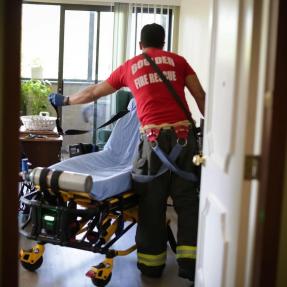 A paramedic prepares a gurney in a hospital room.