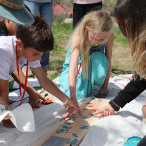 A group of students add their thumb prints to The Nest sign.