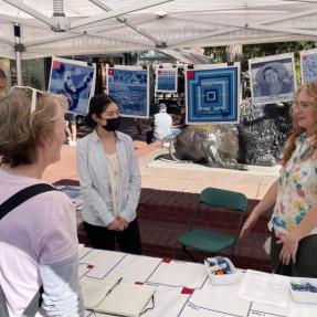 Woman talking with community members behind a table with fabric