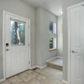 Entry foyer with tile flooring, a white door, and natural light.