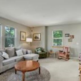 Spacious living room with two sofas, a TV, and large windows