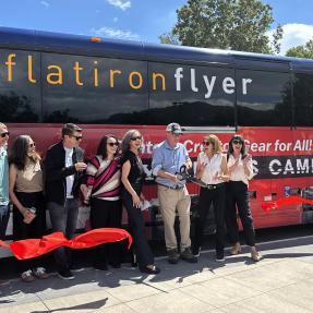 Electeds and other officials cutting a red ribbon in front of a bus at the Downtown Boulder Station Expansion celebration