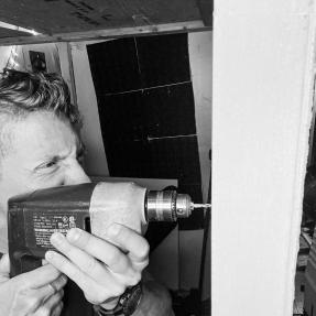 Andy using a drill to renovate a music studio. 