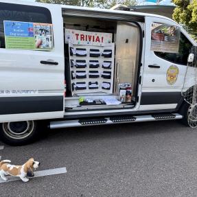 Large white van with a board of trivia questions inside the side door