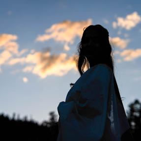 Silhouette of a woman looking off into a sunset. 