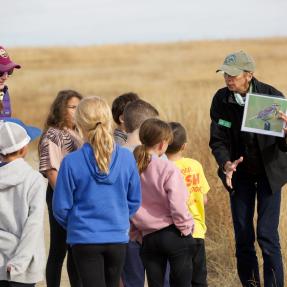 OSMP Volunteer Naturalist showing a group of students a map in the field.