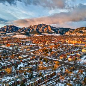 Aerial view of City of Boulder toward the Flatirons at dusk with a dusting of snow