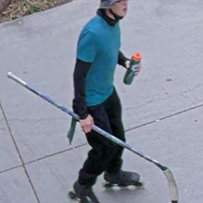 Right profile image of man in blue shirt, long sleeves, helmet and skates holding a hockey stick