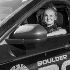 Boulder Police Officer (female) smiles from a patrol car in a welcoming way
