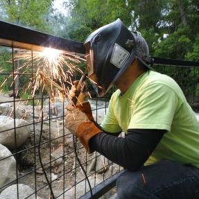 City employee welding a safety barrier over Boulder Creek