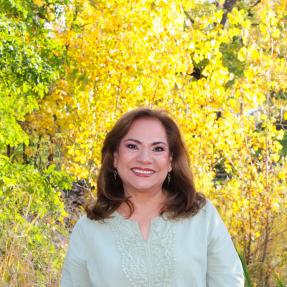 Person standing with a fall foliage background