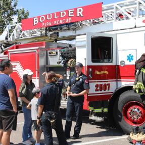 Boulder Fire-Rescue staff speaking with community members in front of a fire engine at What's Up Boulder event