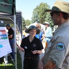 Boulder Parks and Rec employee and OSMP employee speaking together in front of a display at What's Up Boulder event