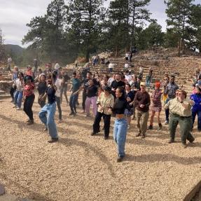 A large group of people dancing at Sunrise Amphitheater on Flagstaff Mountain.