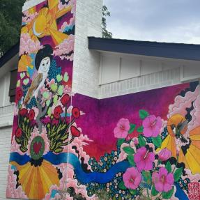 Mural of an owl and flowers on the side of a garage