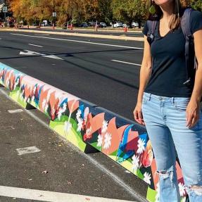 Artist Talia Swartz Parsell next to designs featured on tall concrete curbs along Baseline Road.