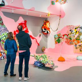 Attendees of a gallery admiring abstract work on a wall
