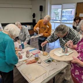 Older Adults participating in a pottery class. 
