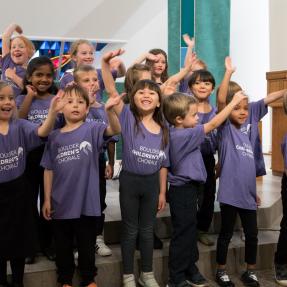 Children waving and smiling who are part of a children's chorale