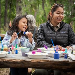 child and ranger painting rocks in park