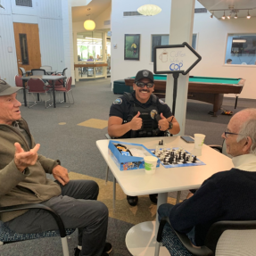 Two older adult men playing a game with a Boulder Police Officer who is giving two thumbs up to the camera.