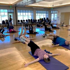 Older adults laying on yoga mats doing a fit and strong workout. 