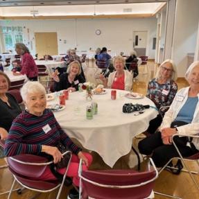 Group of older adult women sitting around a table at the OAS Spring Social. 