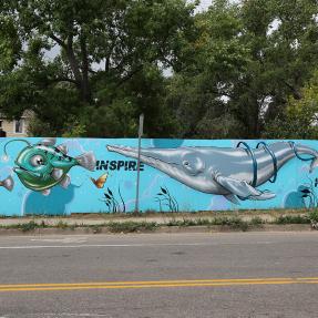 Mural on a neighborhood fence with fish and the words 'inspire' and 'hope'