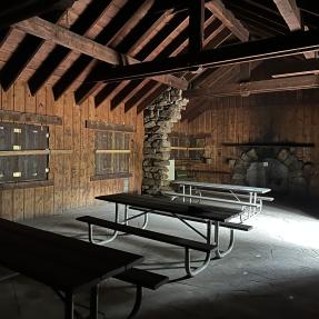 Inside Green Mountain Lodge, a rustic building with picnic tables and stone columns.