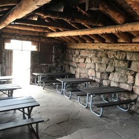 Six picnic tables inside the Halfway House, three on each side with a row down the middle.