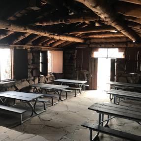 Inside the Halfway House with six picnic tables, two windows and the door let in light.