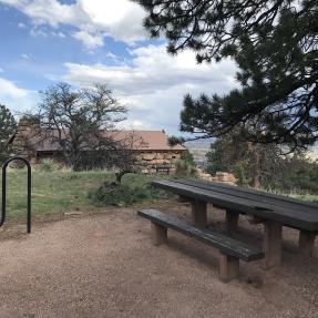 A picnic table and bike rack with the Halfway House behind.