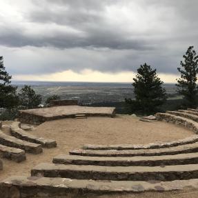 Stone seating circling down toward the center of Sunrise Amphitheater with Boulder down below.