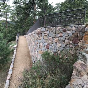 A dirt ramp goes down along a rock wall.