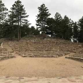 Standing on the edge of the stone stage, the Sunrise Amphitheater center circle is in front, then rows of stone seats circling behind.